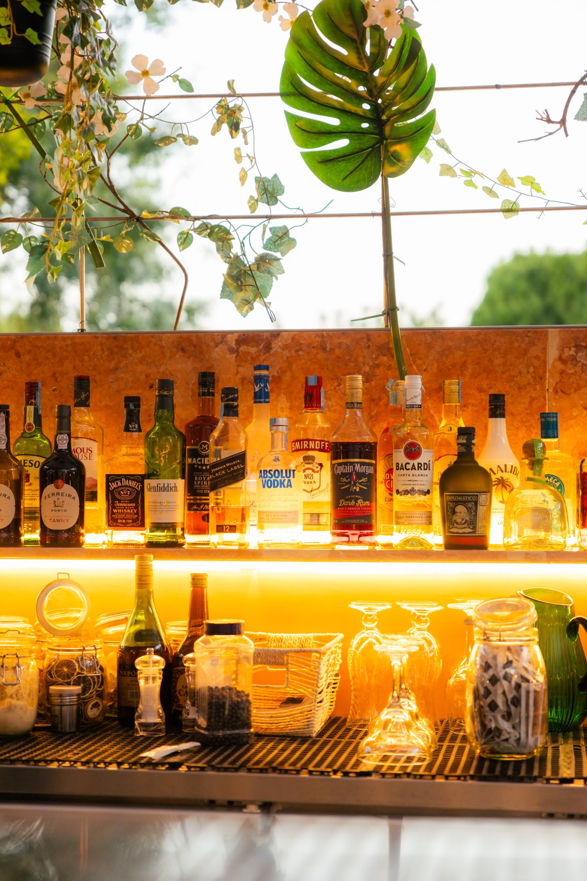 Prateleira de garrafas do bar iluminada por luz âmbar quente