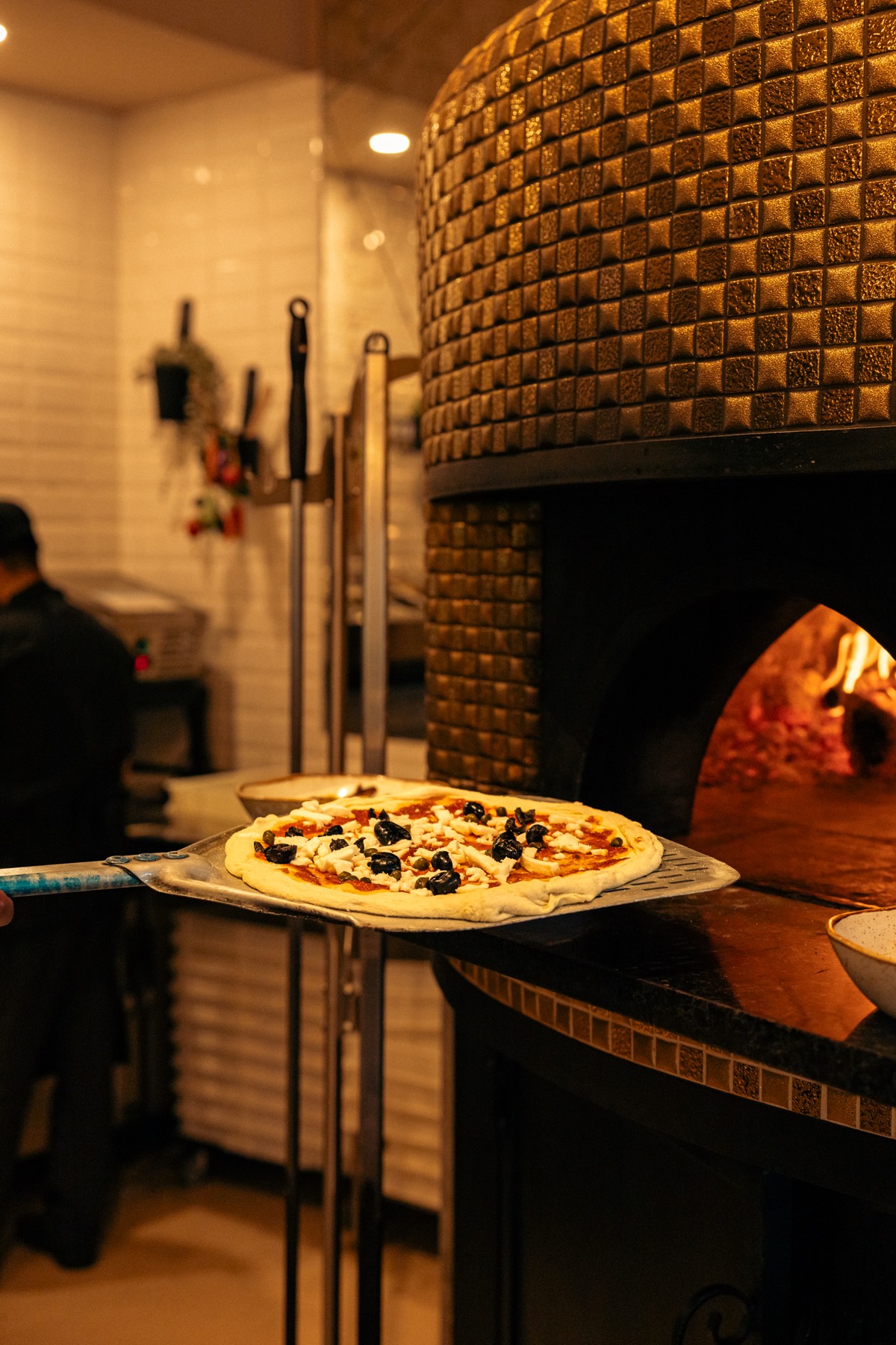 Pizza na pá de madeira a entrar no forno a lenha