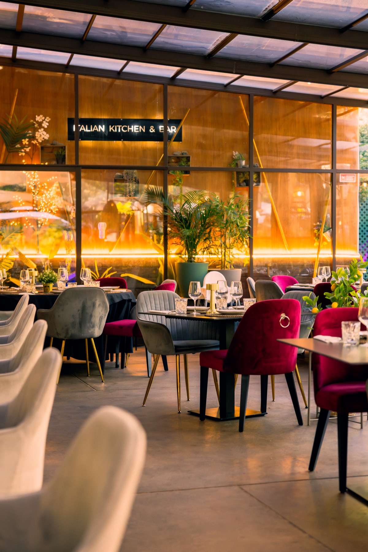 Sala coberta com painel de vidro âmbar iluminado e letreiro Italian Kitchen & Bar