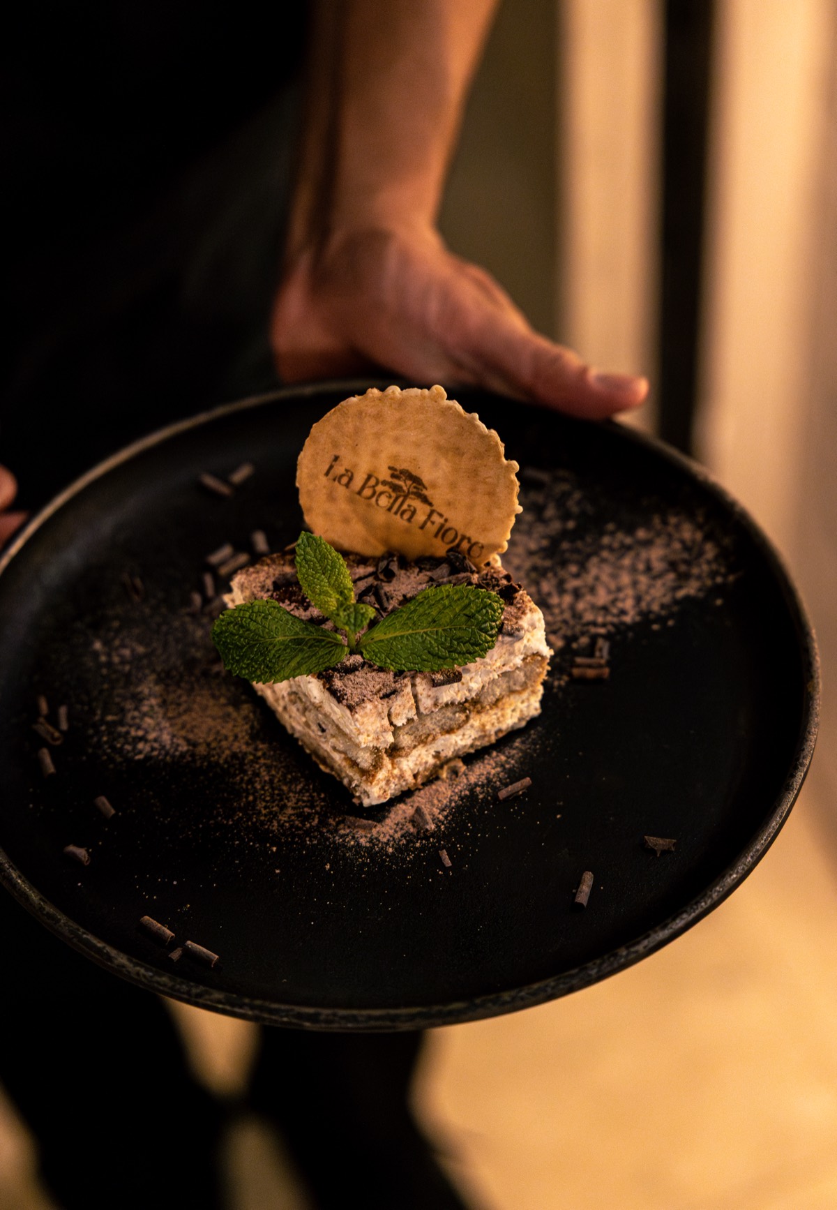 Fatia de tiramisu polvilhada com cacau e folha de hortelã